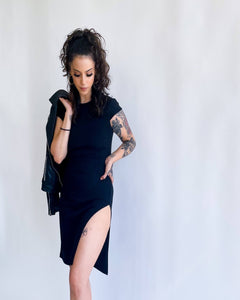 curly haired woman in black ribbed dress with high slit on one side 